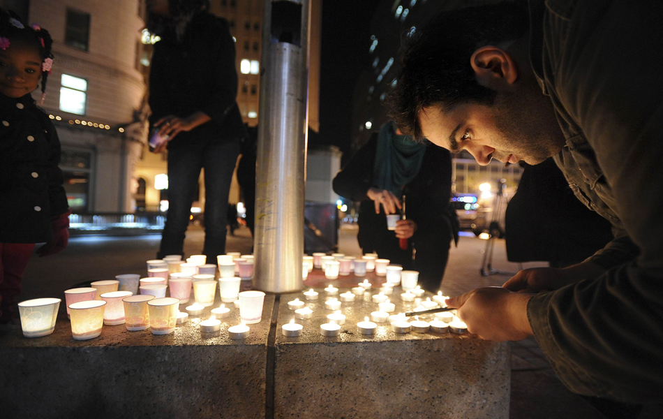 Mario Buda acende velas em Oakland, California, durante vigília em homenagem às vítimas do tiroteio em Connecticut  