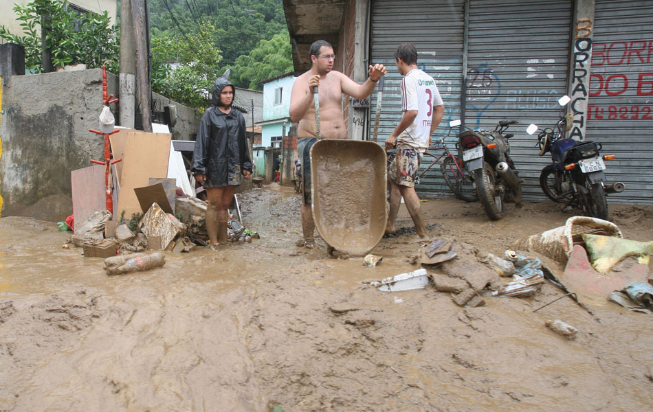 Pessoas retiram lama de suas casas depois das enchentes em Xerém, Baixada Fluminense.