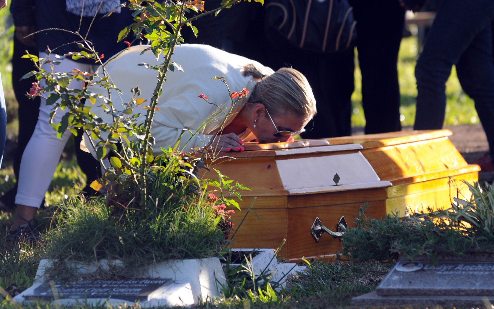 28 de janeiro - Livia Oliveira, mãe de Heitor, se ajoelha para beijar o caixão do filho durante enterro