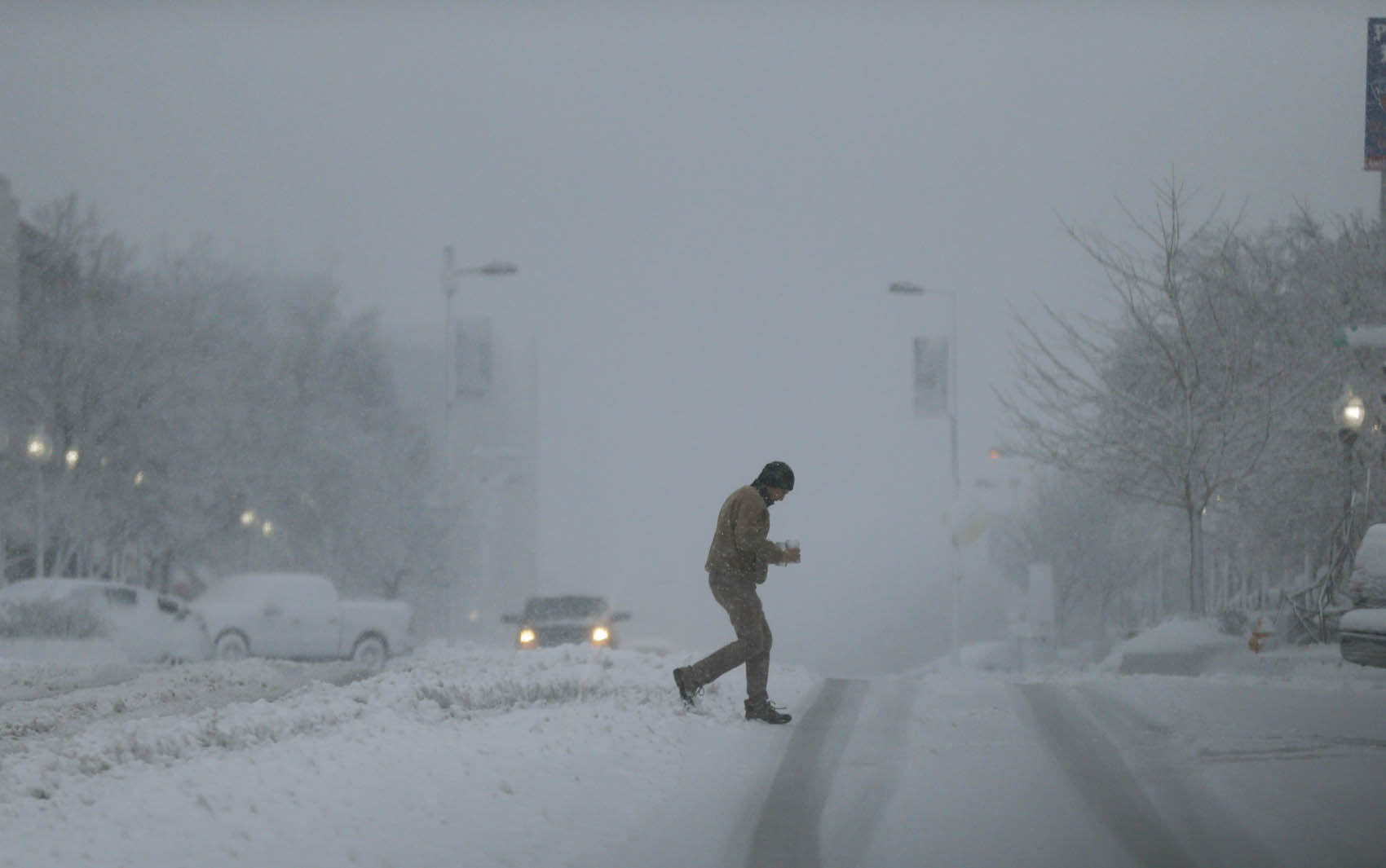 pedestre atravessa a rua debaixo de forte nevasca em Lawrence, Kansas.