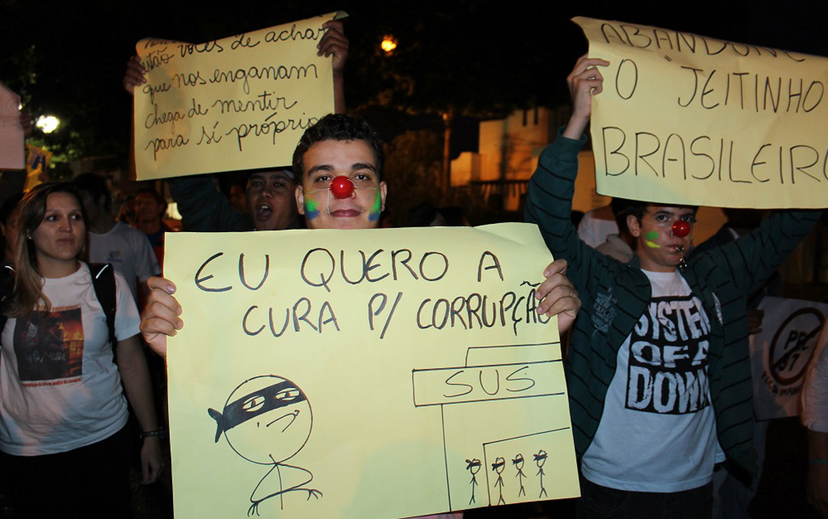 Manifestante com rosto pintado, nariz vermelho e cartaz contra a corrupção em Nova Andradina, a 297 km de Campo Grande, MS