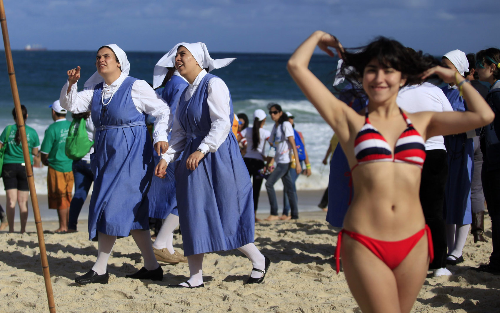 26/7 - Freiras caminham entre banhistas e peregrinos na praia de Copacabana