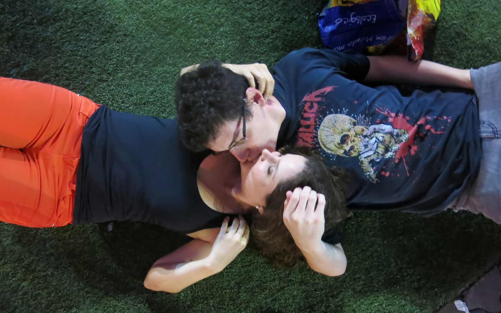 Deitados na grama, o gaúcho Guilherme Zamboni e a goiana Yanelli Castro se beijam antes do show do Sepultura