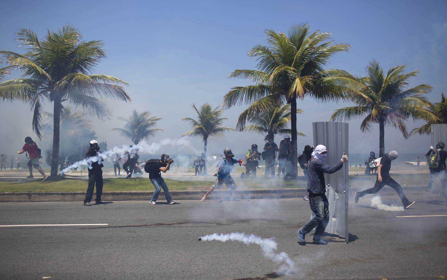 Mascarados reagem a bombas de gás atiradas por militares durante protesto contra o leilão do pré-sal