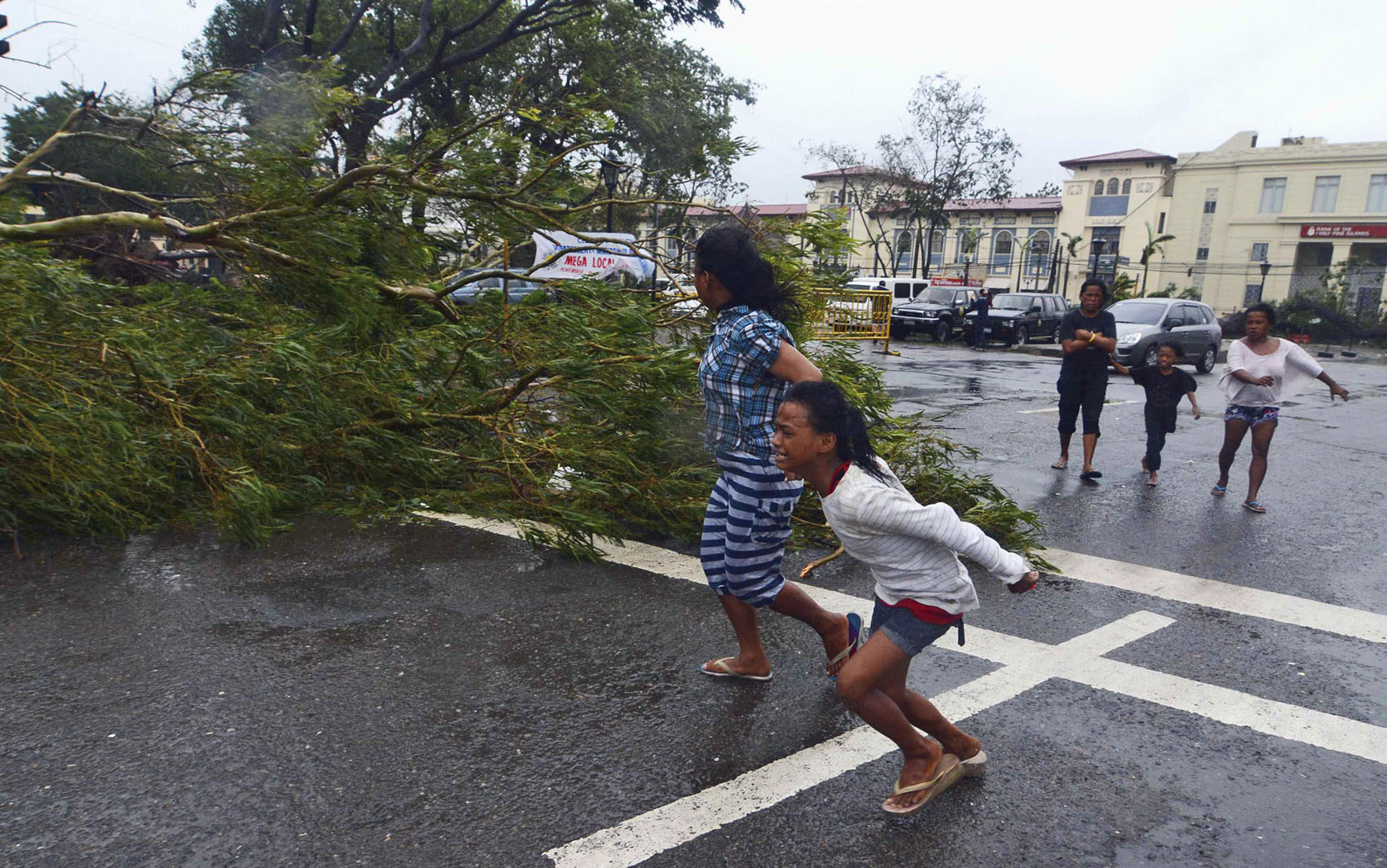 8/11 - Moradores correm próximo de uma árvore caída durante fortes ventos na passagem do tufão que atingiu a região central das Filipinas.