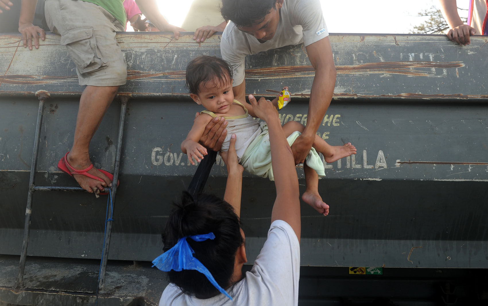 9/11 - Moradores ajudam criança resgatada após a passagem do Tufão em Tacloban, leste da ilha de Leyte.