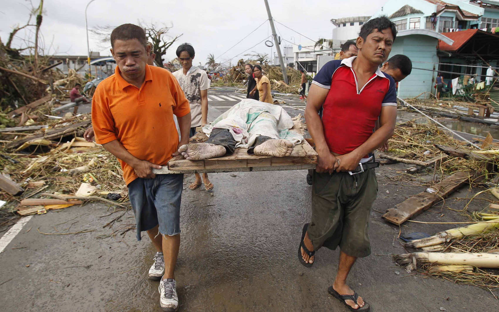 9/11 -Sobreviventes carregam o corpo de uma pessoa morta durante a passagem do tufão Haiyan na cidade Tacloban