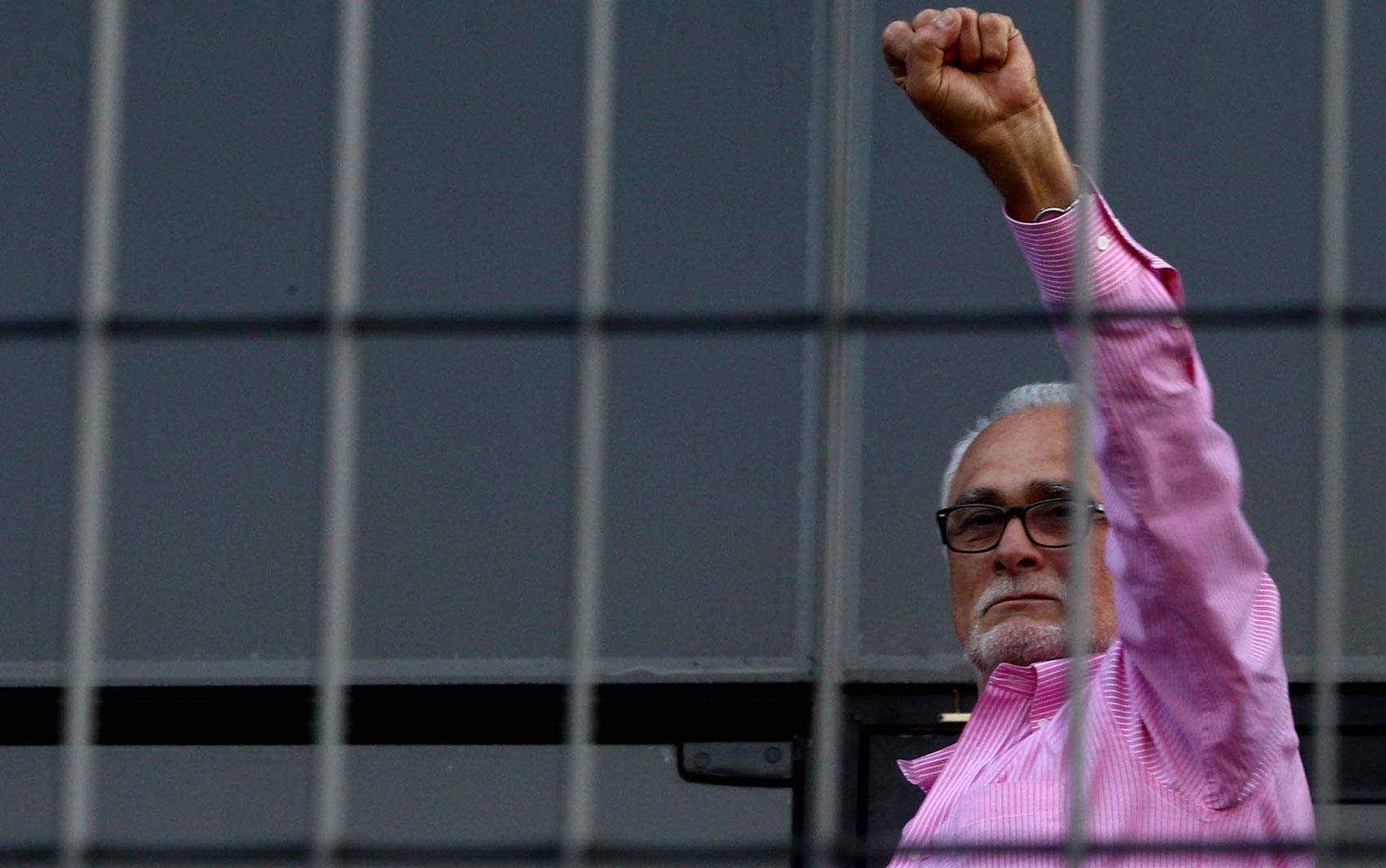 José Genoino ergue o braço à porta da sede da Polícia Federal de São Paulo, antes de se entregar para a prisão. Militantes de esquerda foram ao local para prestar apoio