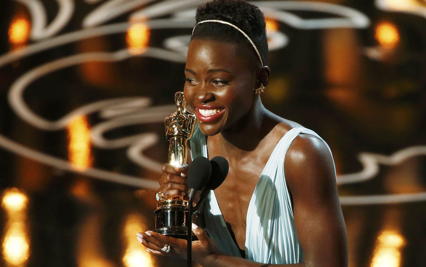 Lupita Nyong'o, de '12 anos de escravidão', leva o Oscar de Atriz Coadjuvante. Ela é aplaudida de pé pela plateia. Durando o discurso, ela se emociona e quase chora.