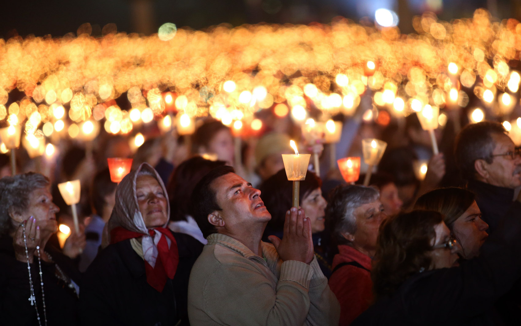 Adoradores rezam durante uma vigília à luz de velas no santuário Nossa Senhora de Fátima, em Portugal. Todos os anos, em 12 e 13 de maio, dezenas de milhares de fiéis católicos vão em peregrinação ao santuário da Fátima para rezar e participar de missas