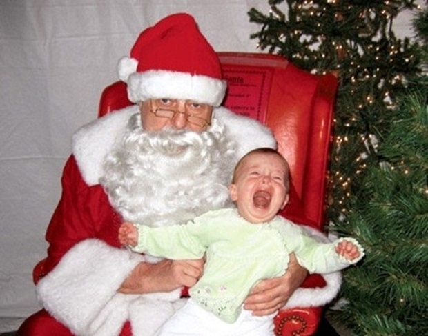 Papai noel aparentemente cansado com criança chorona no colo  (Foto: Reprodução)