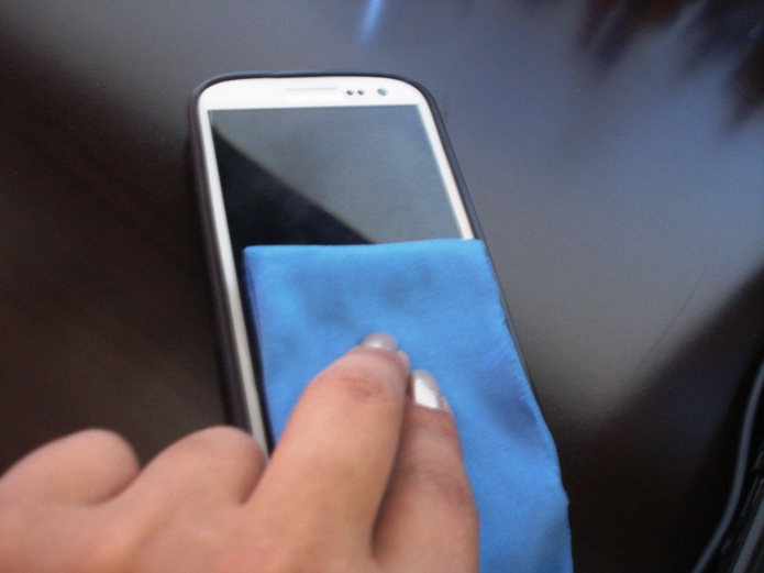 Limpando o smartphone com pano de microfibra (Foto: Lívia Dâmaso)