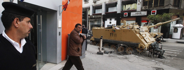 Homem deixa agência bancária fortemente policiais nesta segunda-feira (21) no Cairo (Foto: AP)