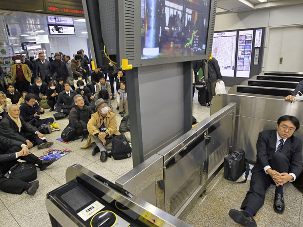 Usuários assistem à TV local após o terremot em estação de trem de Tóquio (Foto: Hiro Komae/AP)