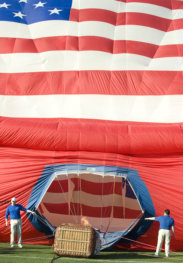 Funcionários do banco que bancou a construção do balão, o PNC, seguram abertura da grande 'bandeira' enquanto estrutura é inflada (Foto: AP)