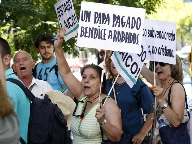 Manifestantes se reúnem em Madri levantando placas com mensagens contra os supostos altos custos gerados pela visita papal (Foto: Andrea Comas/Reuters)