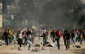 Jovens palestinos jogam pedras contra soldados israelenses perto de Tulkarem, na Cisjordânia, em janeiro de 2009 (Foto: Arquivo AFP)