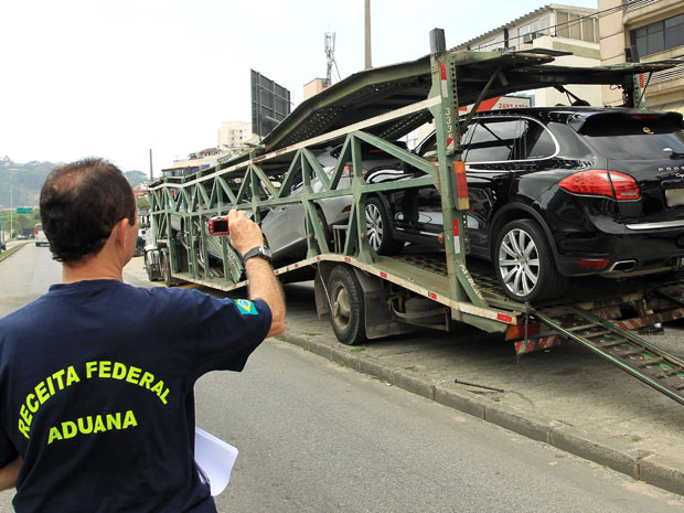 Agente da Receita Federal fotografa carros importados apreendidos em operação da Polícia Federal na Barra da Tijuca, Zona Oeste do Rio (Foto: Gabriel de Paiva/Agência O Globo)