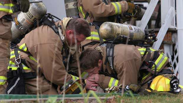 Os bombeiros Jared Thompson (esquerda) e Jamie Giese fazem respiração artificial em cão que acabaram de resgatar em incêndio em casa em Wausau, no estado americano de Wisconsin, nesta terça-feira (19). O cão era um labrador de 7 anos chamado Coda (Foto: AP Photo/Dan Young/Wausau Daily Herald)