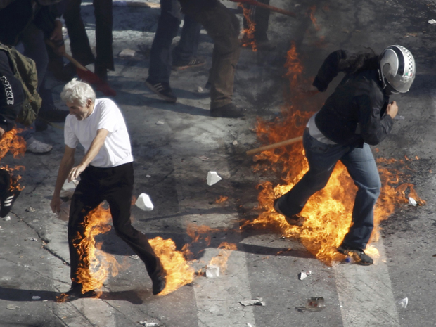 Manifestantes são atingidos por bombas durante confronto com a polícia perto do Parlamento grego (Foto: Reuters)