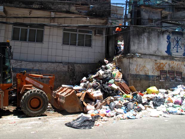 Um trator da Comlurb tenta recolher uma grande quantidade de lixo espalhada na rua (Foto: Bernardo Tabak/G1)