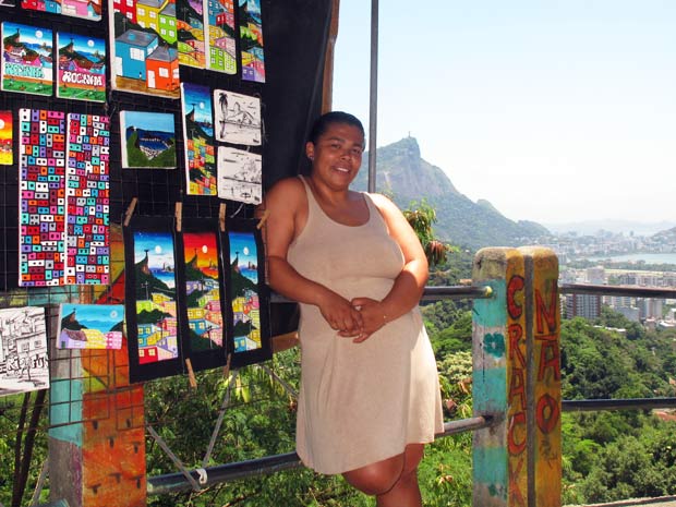 Raquel posa ao lado dos quadros, inspirados na paisagem que se vê de mirantes da favela (Foto: Bernardo Tabak/G1)