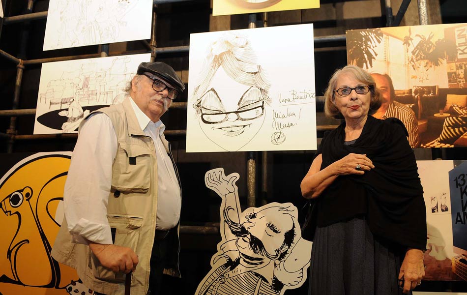 Sérgio Rodrigues e a mulher, Vera Beatriz, ao lado da caricatura que ele fez para a  musa