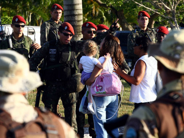 Mulher tenta passar por homens do Exército com uma criança no colo durante manifestação de policiais militares na Assembleia Legislativa, em Salvador (Foto: Lúcio Távora/Agência A Tarde/AE)