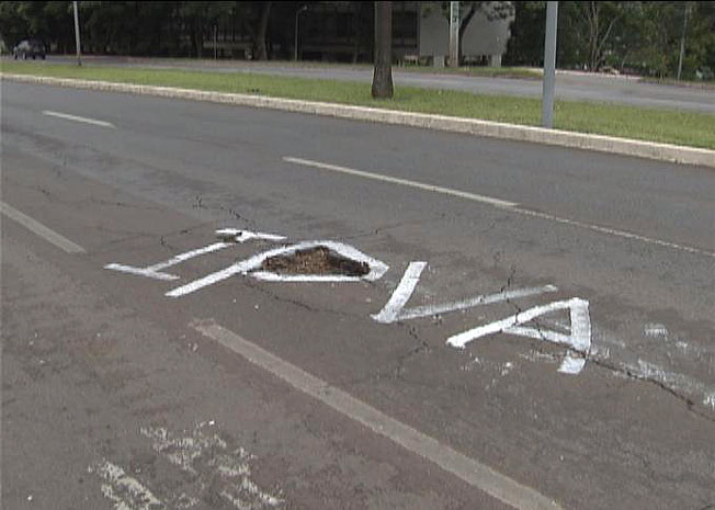 Protesto no Eixinho na L Norte transforma os buracos na pista em letras: IPVA. Imposto pago por donos de carros para evitar que as pistas fiquem nesse estado. (Foto: Tv Globo/Reprodução)