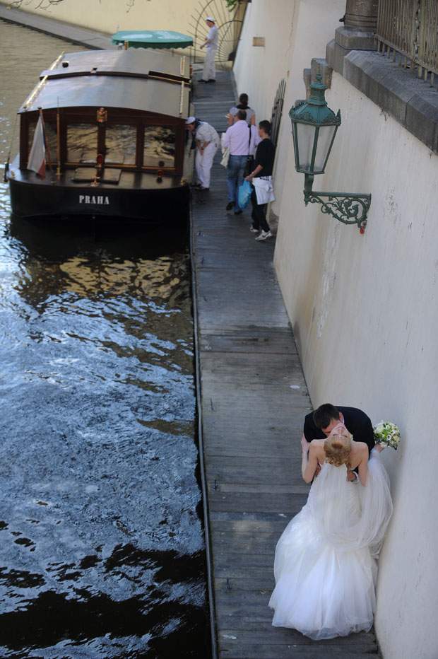 Recém-casado beija o pescoço de sua esposa à beira de um rio de Praga (Foto: Michal Cizek/AFP)