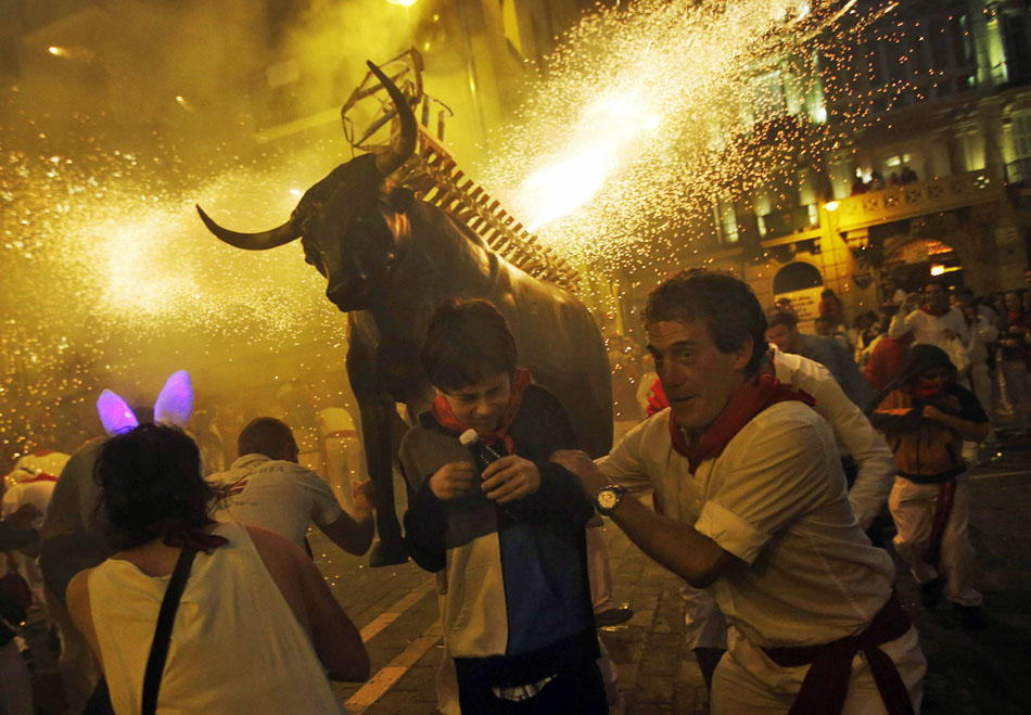 Pessoas se assustam com fogos de artifício lançado por uma estrutura metálica em formato de boi no quinto dia do festival de São Firmino em Pamplona.
