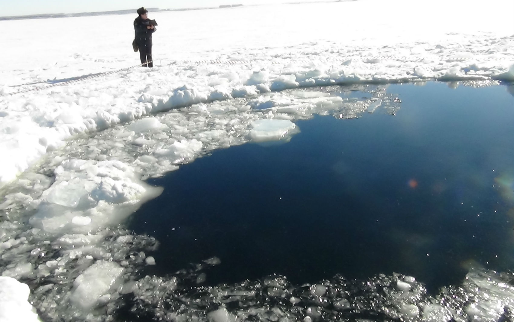 Pessoa observa buraco provocado por suposto meteorito em lago congelado Chebarkul na Rússia.