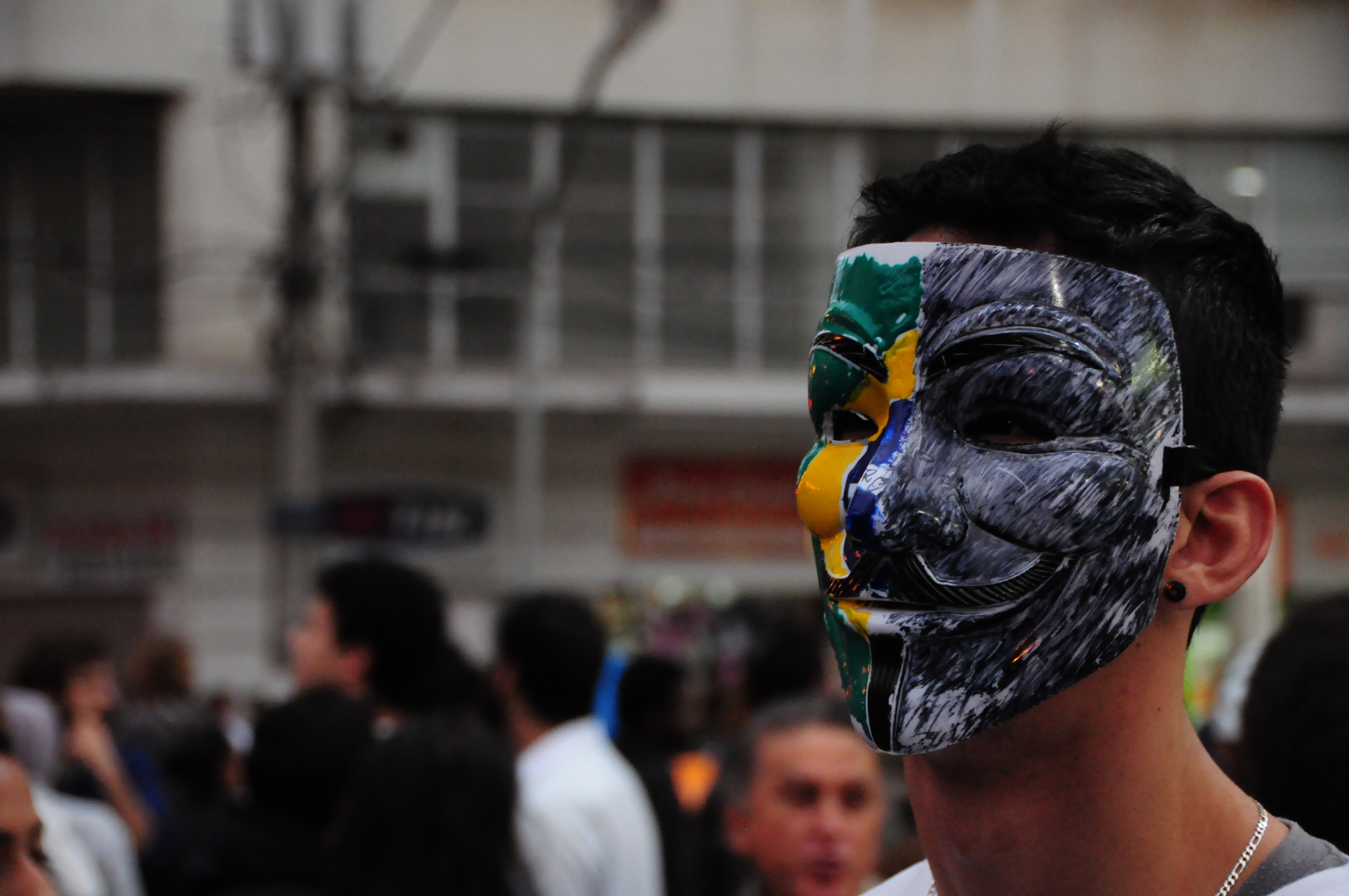 Manifestante utiliza máscara com metade da bandeira do Brasil no terceiro dia de protestos 