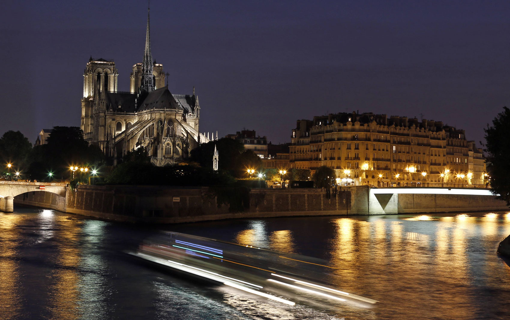 À noite, Paris faz jus ao famoso apelido de 'Cidade-Luz'. Diversos monumentos ganham iluminação especial. Entre eles, a Catedral de Notre-Dame. que pode ser vista à esquerda, na foto.