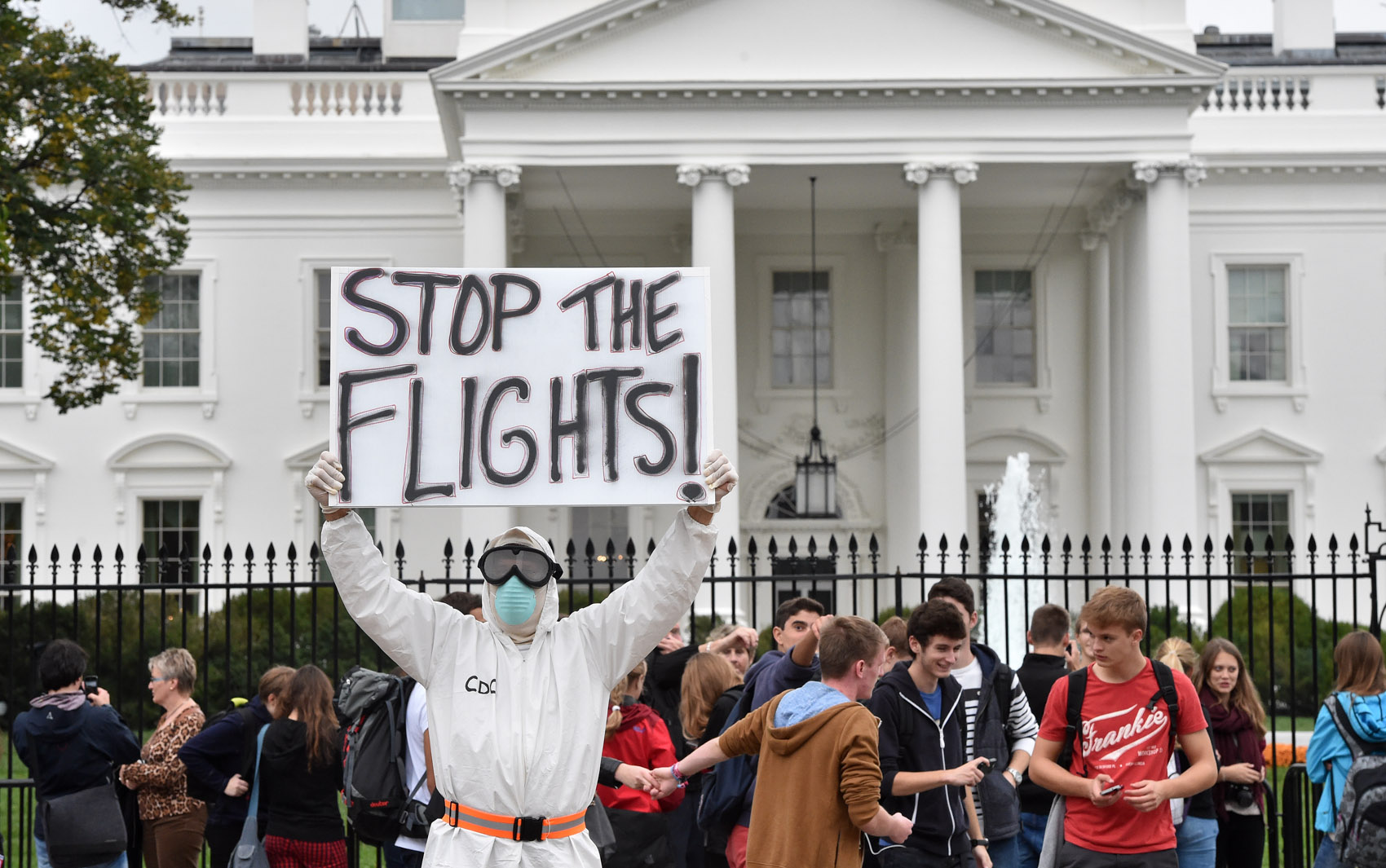 16/10 - Um manifestante vestido com roupa de proteção segura um cartaz pedindo que parem todos os voos a partir da África Ocidental durante protesto em frente à Casa Branca, em Washington, nos Estados Unidos 